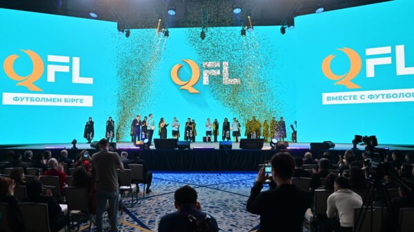 Presentation event for the Qazaqstan Football League with large QFL logo on screen, confetti, and people on stage.